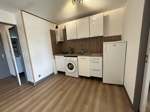 A compact kitchen with a washing machine, a refrigerator, and wooden flooring. - Lovely 2-bedroom apartment near Richelieu beach, Cap d'Agde (LE CAP D AGDE)