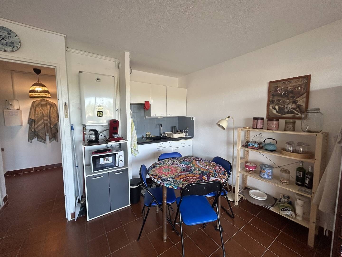 A compact kitchen with a dining table, chairs, a microwave, and a coffee maker.