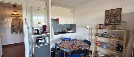 A compact kitchen with a dining table, chairs, a microwave, and a coffee maker.