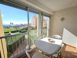 A balcony with a table and chairs, a view of a park, and buildings in the distance. - CAP D'AGDE - Plage du Môle / Réf 204 (CAP D'AGDE)