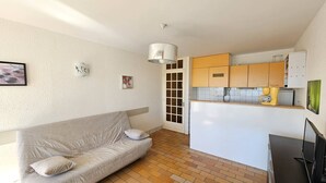 Un espacio habitable pequeño con sofá, kitchenette y televisor.