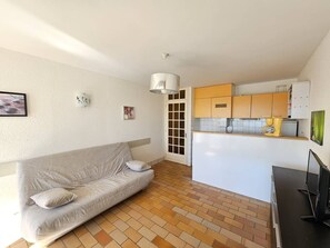 Ein kompakter Wohnbereich mit Sofa, Küchenzeile und Fernseher.