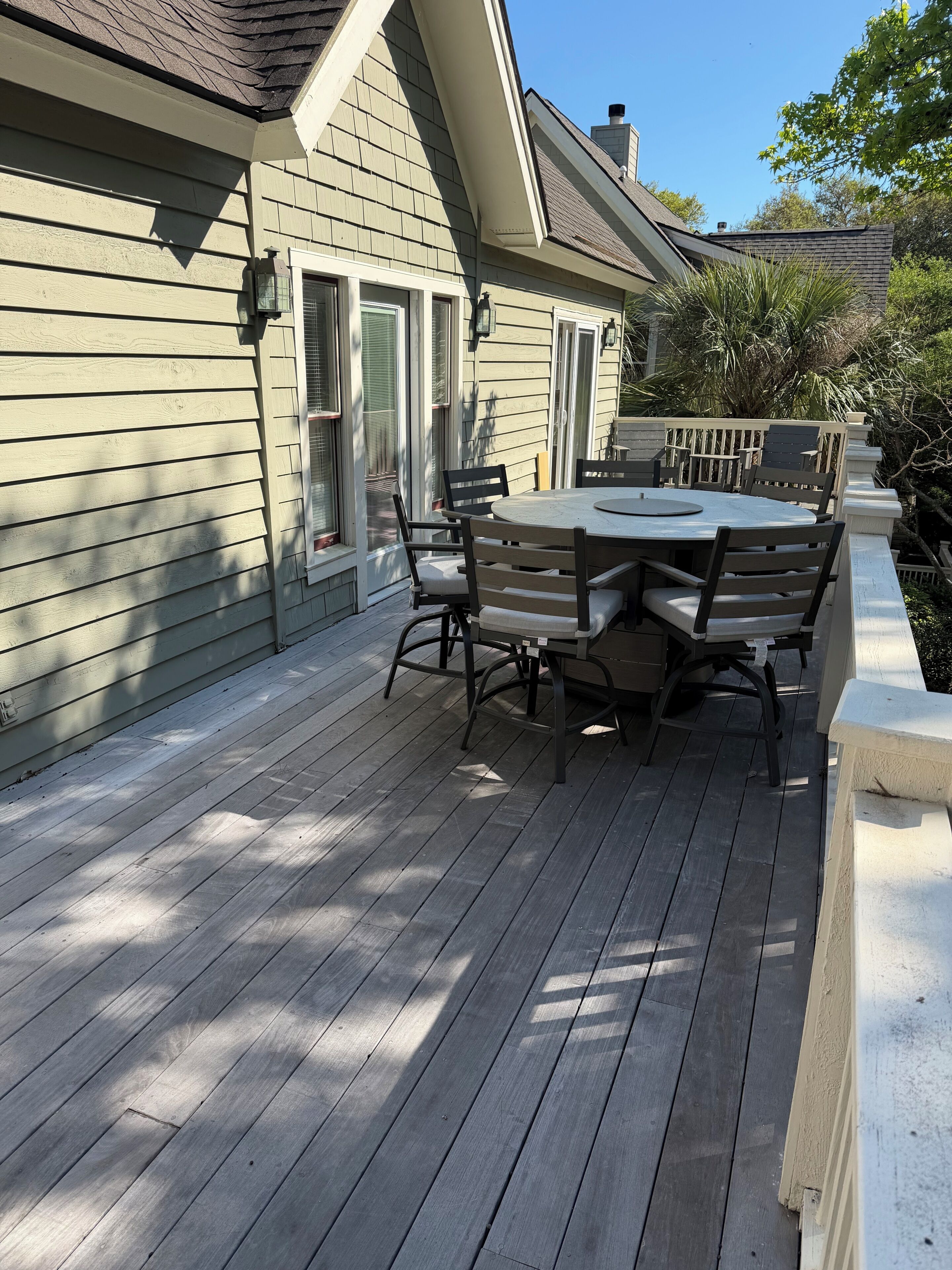 A deck with a table and chairs, a window, and a door.