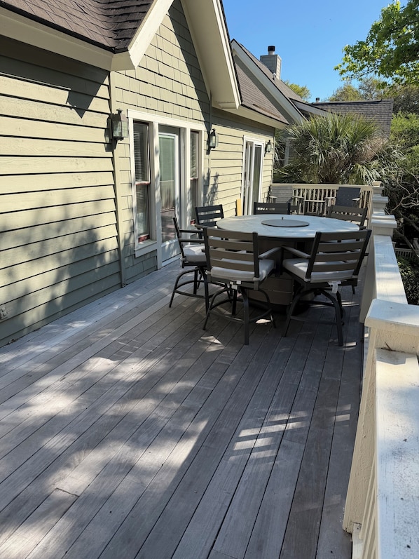 A deck with a table and chairs, a window, and a door.
