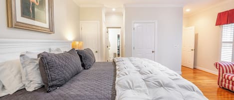 Een slaapkamer met een groot bed, een deur naar een andere kamer en een raam met zonwering.