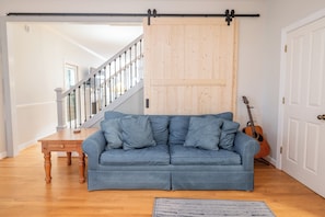 Une pièce avec un canapé bleu, une table en bois, une guitare et une porte coulissante.