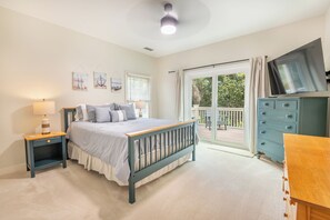 Un dormitorio con cama, cómoda, televisor y balcón.