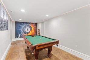 A pool table in a room with a mural, white walls, and a wooden floor. - Welcoming 4-bedroom house with AC in vibrant St. Louis (St. Louis)
