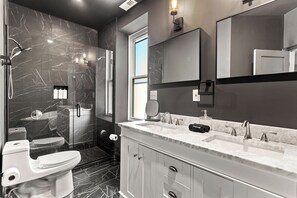 Une salle de bain moderne avec un sol en marbre, un meuble-lavabo à deux vasques, un grand miroir et des toilettes.