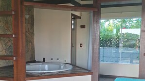 Une pièce dotée d’un sol carrelé, d’un plafond en bois, d’un mur en pierre, d’une fenêtre offrant une vue agréable et d’un lit recouvert d’une couverture à motifs.
