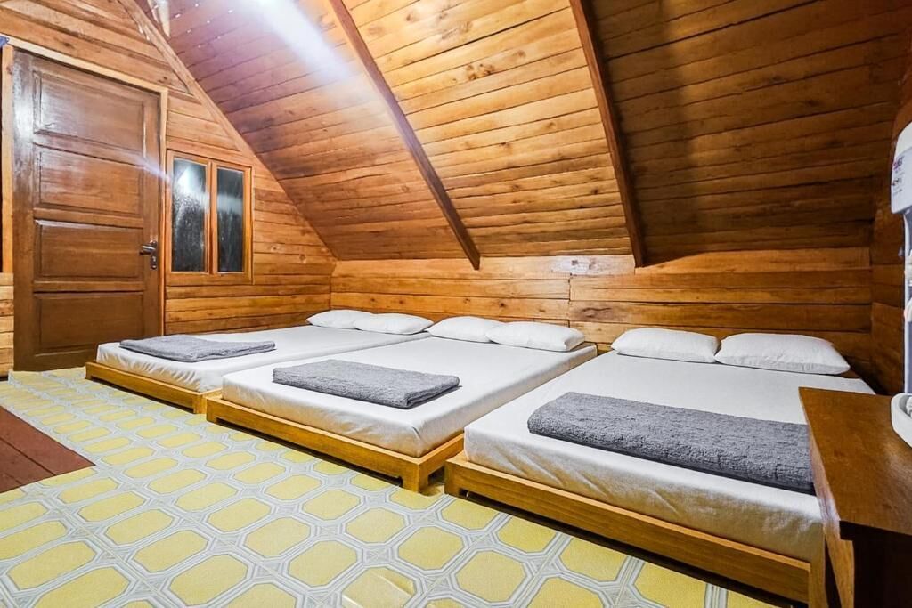 A wooden cabin with three beds, a wooden door, and a patterned floor.