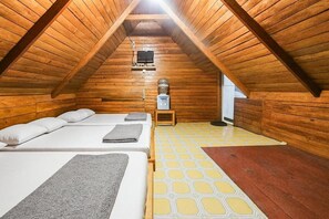 A cozy attic bedroom with wooden walls, two beds, a heater, and a window. - Cozzy Villa Tb (BANDUNG)