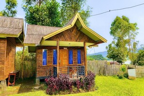 A wooden cabin with a porch, a small staircase, and a view of the surrounding greenery. - Cozzy Villa Tb (BANDUNG)