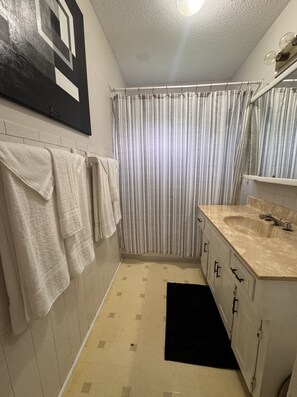 Ein Badezimmer mit Fliesenboden, Waschbecken mit Spiegel und Duschvorhang.