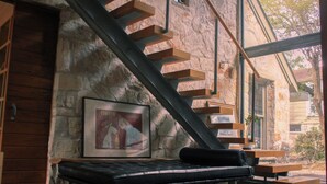 Ein modernes Interieur mit einer Steinsäule, einer Treppe, einer Bank und einem gerahmten Bild.