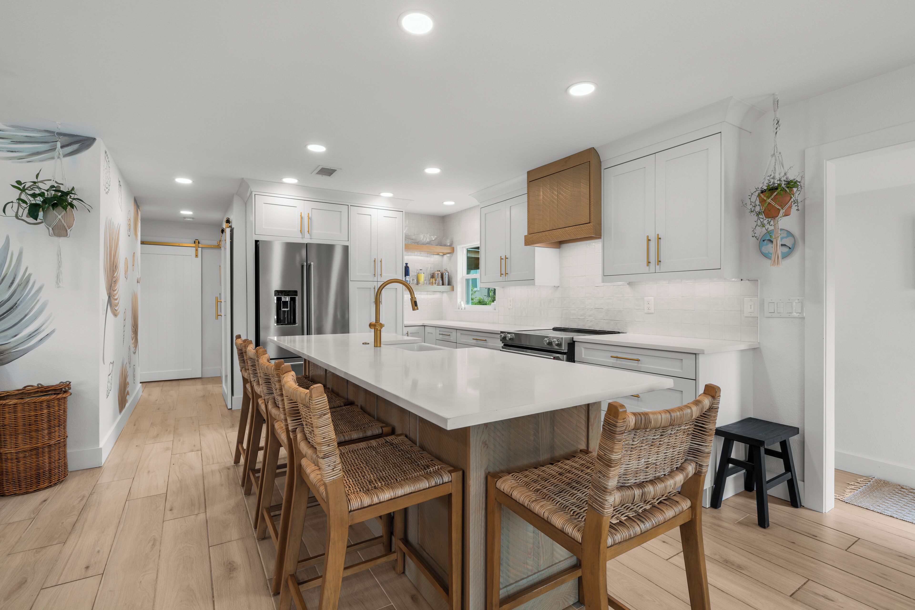 Una cocina moderna con armarios blancos, una isla grande y sillas de mimbre.
