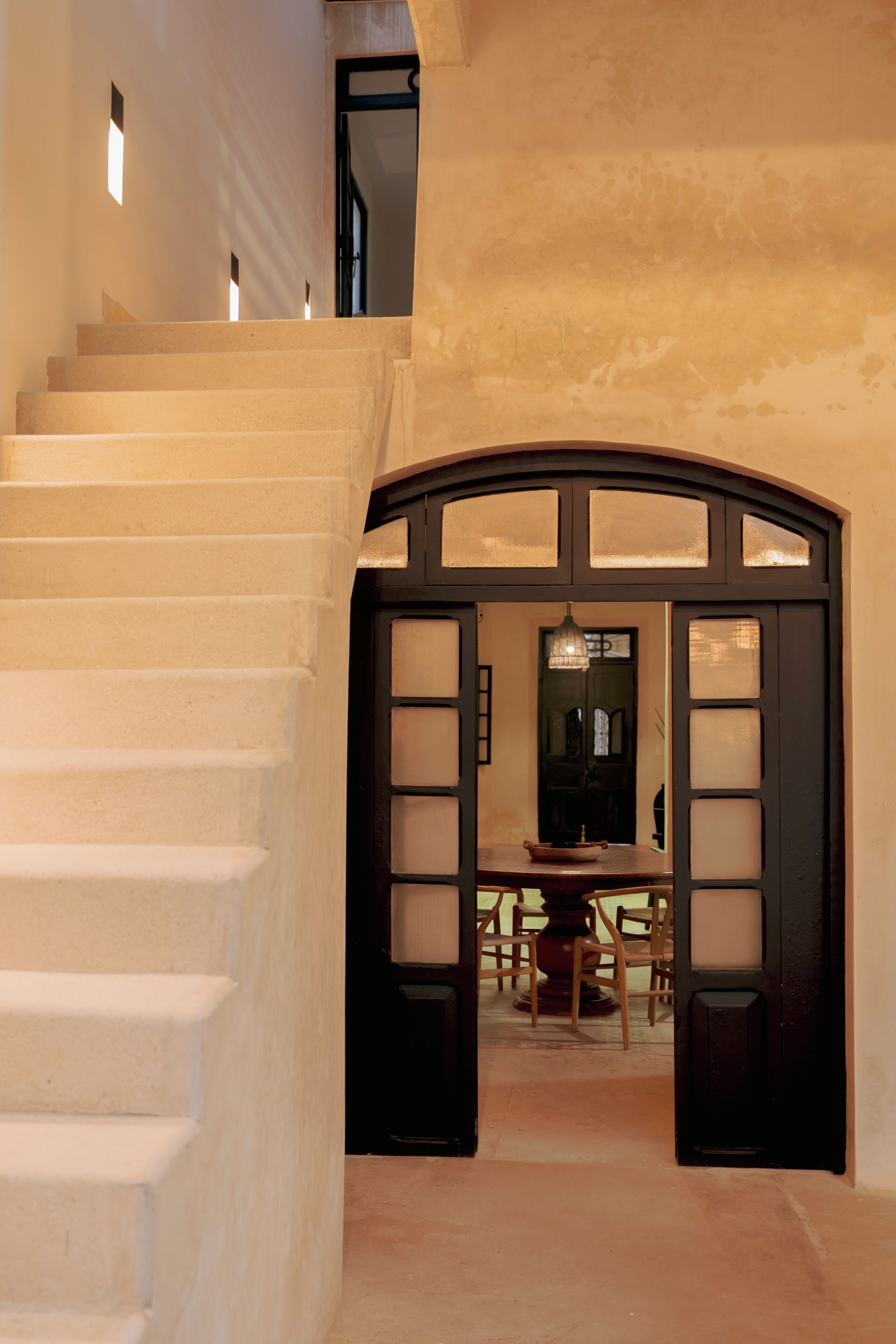 A staircase leading to a dining area with a table and chairs.