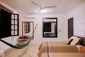 Ein Schlafzimmer mit Bett, Stuhl, Hängematte, Deckenventilator und einem Fenster mit Jalousien.