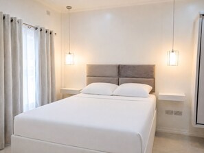 Ein modernes Schlafzimmer mit einem großen Bett, zwei Nachttischen und einem Kopfteil.