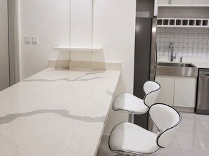 Eine moderne Küche mit weißer Arbeitsplatte, Edelstahlgeräten und einer integrierten Spüle.