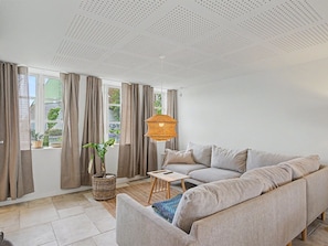 Una sala de estar moderna con un sofá, una lámpara colgante y una ventana con cortinas.