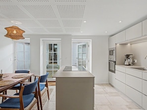 Una cocina moderna con una isla central, electrodomésticos integrados y un comedor con sillas y una mesa.