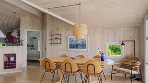 A spacious room with a wooden dining table, chairs, a hanging light fixture, and a window with a view. - "Ronna" - 160m from the sea by Interhome (Otterup)