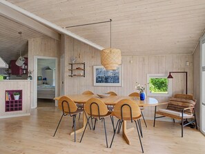 A spacious room with a wooden dining table, chairs, a hanging light fixture, and a window with a view. - "Ronna" - 160m from the sea by Interhome (Otterup)