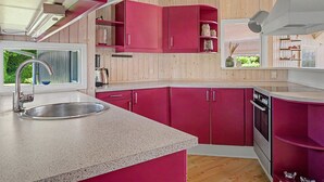 A modern kitchen with pink cabinets, a stainless steel sink, and wooden flooring. - "Ronna" - 160m from the sea by Interhome (Otterup)