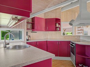 A modern kitchen with pink cabinets, a stainless steel sink, and wooden flooring. - "Ronna" - 160m from the sea by Interhome (Otterup)