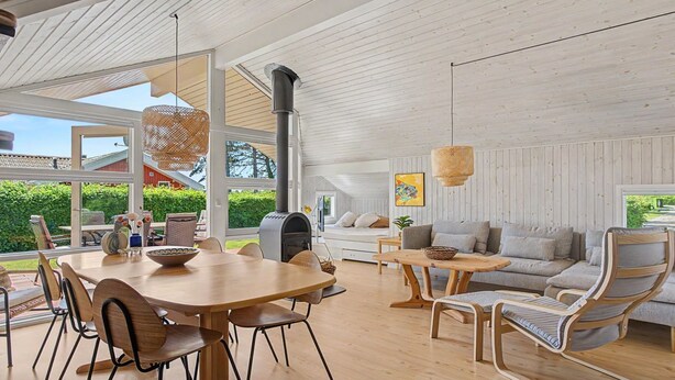 A spacious interior with a wooden dining table, chairs, a sofa, and a fireplace. - "Ronna" - 160m from the sea by Interhome (Otterup)