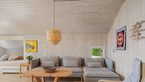 A cozy room with a wooden ceiling, a sofa, a table, and a hanging light fixture. - "Ronna" - 160m from the sea by Interhome (Otterup)