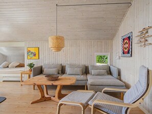 A cozy room with a wooden ceiling, a sofa, a table, and a hanging light fixture. - "Ronna" - 160m from the sea by Interhome (Otterup)