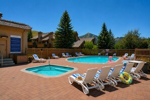 A pool area with two pools, lounge chairs, and a wooden fence. - Alpine Loft | Walk to Ski | Hot Tub | Pool | Deck (Sun Valley)