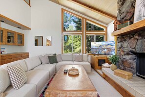 Una sala moderna con un ventanal grande, una chimenea de piedra y una mesa de centro de madera.