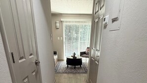 A hallway with a patterned rug, a black bathtub, and a window with blinds. - Braves Retreat 5 Min to Truist Park & The Battery (Smyrna)