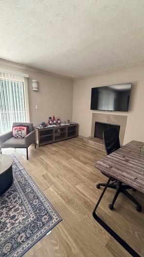 A living room with a flat-screen TV, a fireplace, a sofa, a coffee table, and a patterned rug.