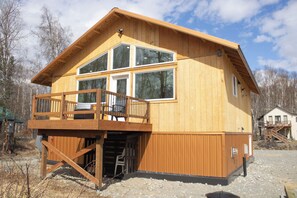 A wooden cabin with a balcony, large windows, and a small porch area. - Welcome to Sky Ranch, a spacious, warm newly built home ready to welcome you. (Talkeetna)
