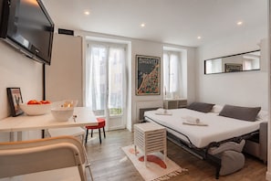 Ein modernes Hotelzimmer mit Bett, Schreibtisch, Stuhl, Fernseher und einem Fenster mit Vorhängen.