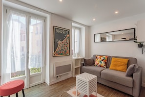 Ein Wohnzimmer mit einer Couch, einem roten Sessel, einem weißen Couchtisch, einer gerahmten Karte und einem Spiegel an der Wand.