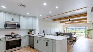 A modern kitchen with built-in appliances, a large island, and a dining area with a view. - Centre Court Pacifica Near Disney, Golf Course, WaterPark (Kissimmee)
