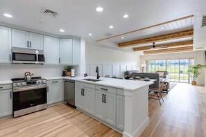 A modern kitchen with built-in appliances, a large island, and a dining area with a view. - Centre Court Pacifica Near Disney, Golf Course, WaterPark (Kissimmee)