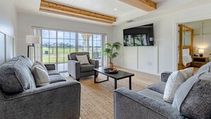A spacious living room with a large window, grey sofas, a coffee table, and a ceiling fan. - Centre Court Pacifica Near Disney, Golf Course, WaterPark (Kissimmee)