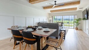A modern dining area with a wooden table, black chairs, and a grey sofa. - Centre Court Pacifica Near Disney, Golf Course, WaterPark (Kissimmee)