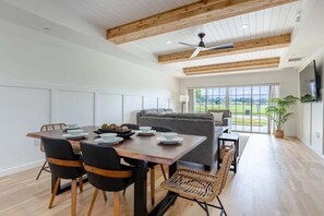 A modern dining area with a wooden table, black chairs, and a grey sofa. - Centre Court Pacifica Near Disney, Golf Course, WaterPark (Kissimmee)