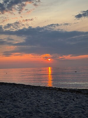 Ein Strand mit Sonnenuntergang über dem Wasser.