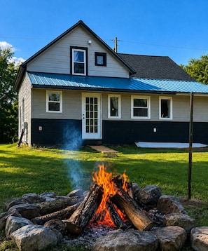 A house with a fire pit in the front yard.