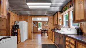 A wooden cabin interior with a kitchen, dining area, and a view of the outdoors. - New Listing! 4 Bedroom Home 2 mins from the Lake-Boating-Fishing-Fire Pit (Trout Lake)