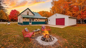 A house with a green roof, a red garage, and a fire pit in the yard. - New Listing! 4 Bedroom Home 2 mins from the Lake-Boating-Fishing-Fire Pit (Trout Lake)