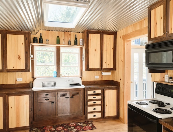 A kitchen with wooden cabinets, a sink, a stove, and a skylight.